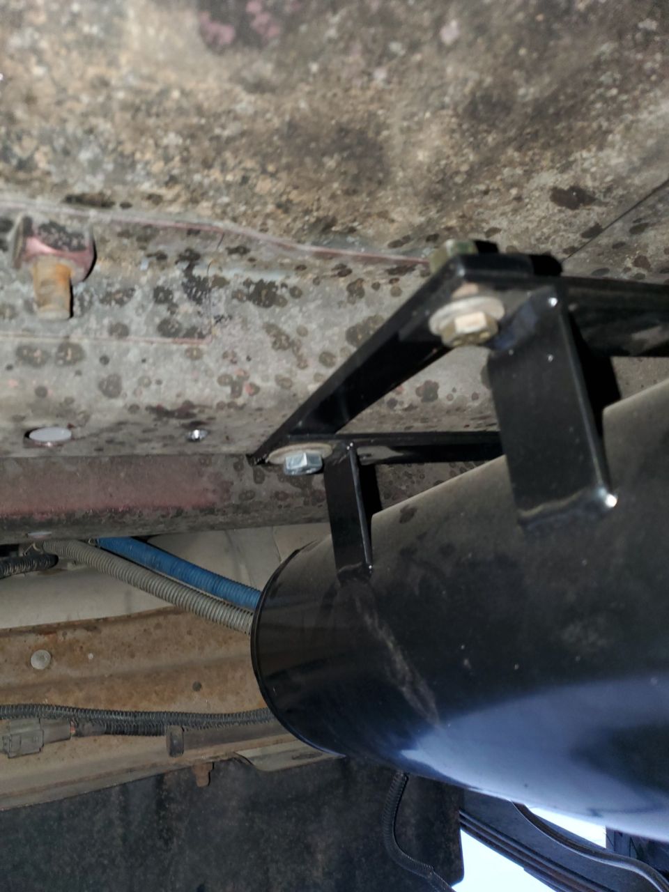 Underbody air tank mount with bolts and brackets attached to vehicle frame