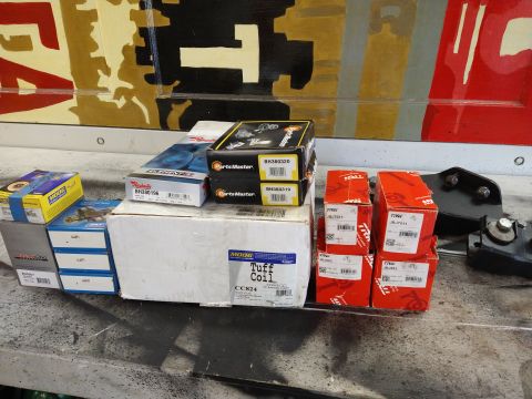 1996 Ford Bronco - Several boxes of automotive parts, including suspension and engine components, are arranged on a surface.