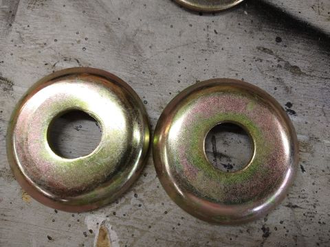 1996 Ford Bronco - Two large, golden-yellow washers with a hole in the center are displayed on a textured, grey surface. The washers have a slightly iridescen…