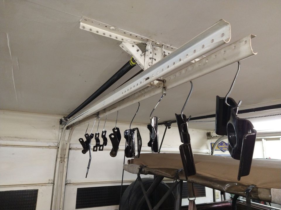 Black painted automotive parts hanging to dry on a ceiling track.