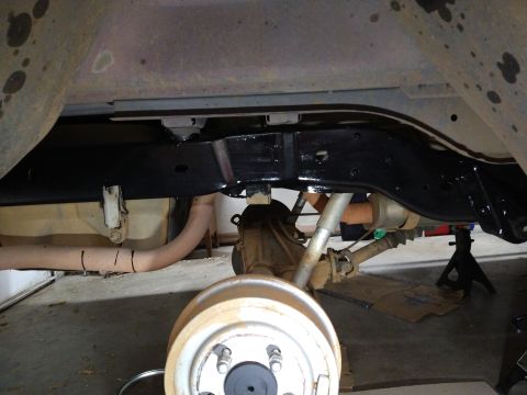 1996 Ford Bronco - Underneath view of a vehicle's frame and suspension system. A black painted frame rail is visible, along with parts of the exhaust system,…
