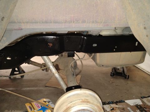 1996 Ford Bronco - The underside of a vehicle, likely a 1996 Ford Bronco, shows a freshly painted black frame rail and rear axle assembly. The vehicle is supp…