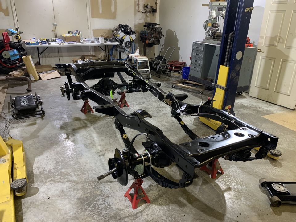 Black Jeep CJ5 frame on jack stands in a garage.