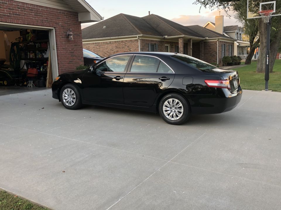 Black 2011 Toyota Camry sedan parked on a concrete driveway.