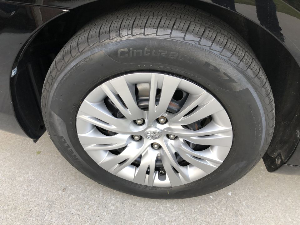 Close-up of a black sedan's front passenger tire and wheel, featuring a Pirelli Cinturato P7 tire and silver Toyota hubcap.