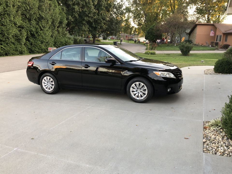 Black 2011 Toyota Camry sedan parked on a concrete driveway.