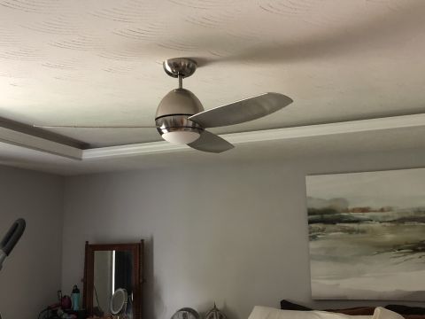1995 Mercury Grand Marquis - A ceiling fan with brushed nickel finish is mounted on a textured white ceiling. The fan has three blades and a central light fixture.