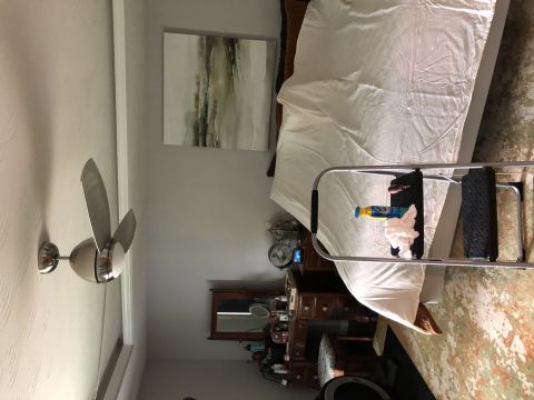 1995 Mercury Grand Marquis - A bedroom scene with a bed covered in a white sheet, a dresser with a mirror, and a ceiling fan.