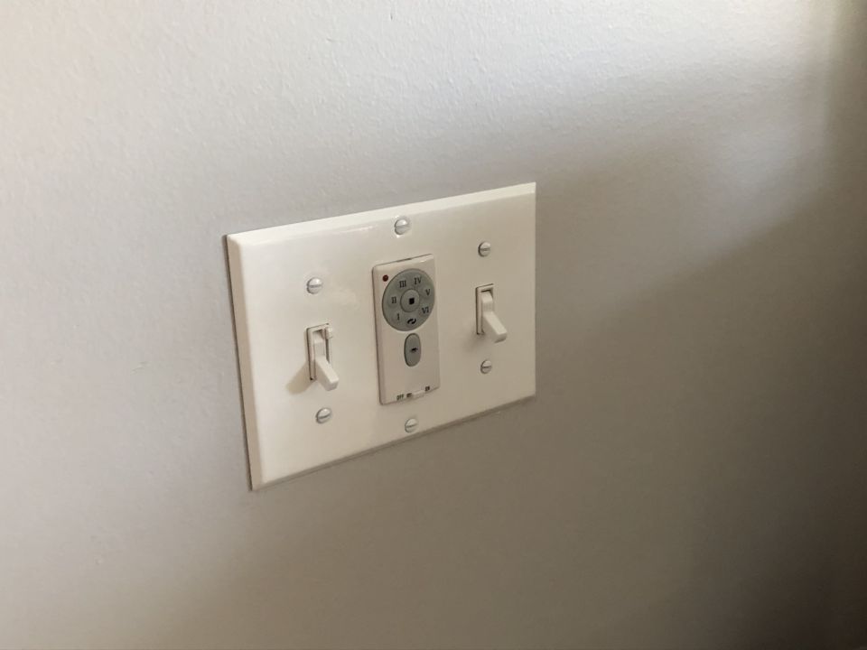 Wall plate with two light switches and a fan speed controller