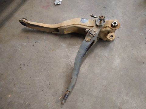 1996 Ford Bronco - This image shows a disassembled front suspension control arm assembly, likely from a 1996 Ford Bronco, lying on a concrete floor. The assem…