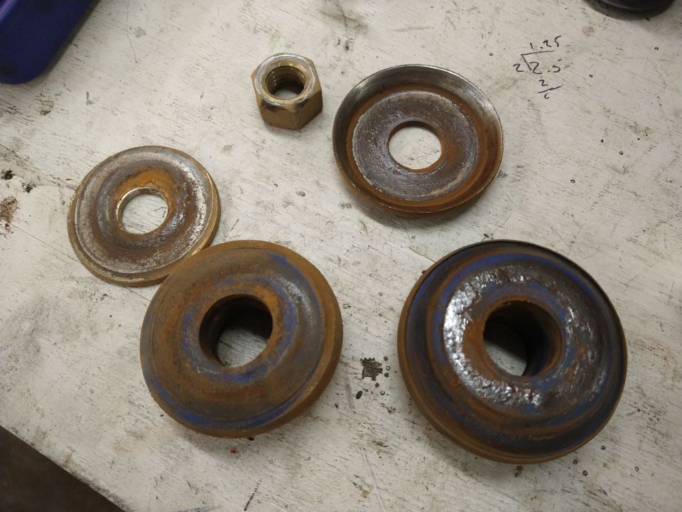 Four worn brake rotors and several nuts on a surface