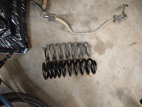 1996 Ford Bronco - A comparison of old and new suspension components, including a sway bar and coil springs, laid out on a concrete floor.