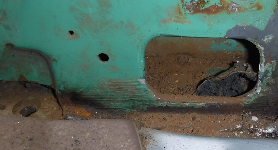 Removal of the recently learned of plate that blocks what would otherwise be a great drain at the base of the b-pillars.  The thin plate is partially pried up here (the two push pins have been removed), revealing the additional expanding foam sucking it down from below.