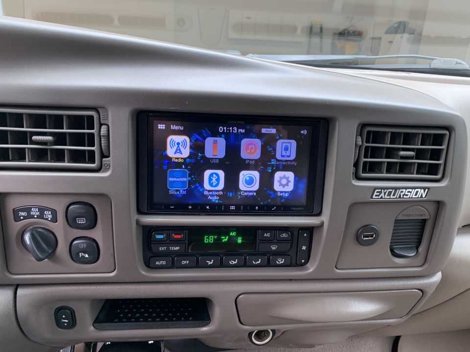 2002 Ford Excursion dashboard with Alpine touchscreen stereo, climate controls, and 4x4 shifter.