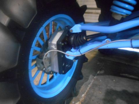 1992 Ford Bronco - A close-up view of the rear wheel assembly of a vehicle, featuring a bright blue rim and suspension components. A visible brake caliper and…