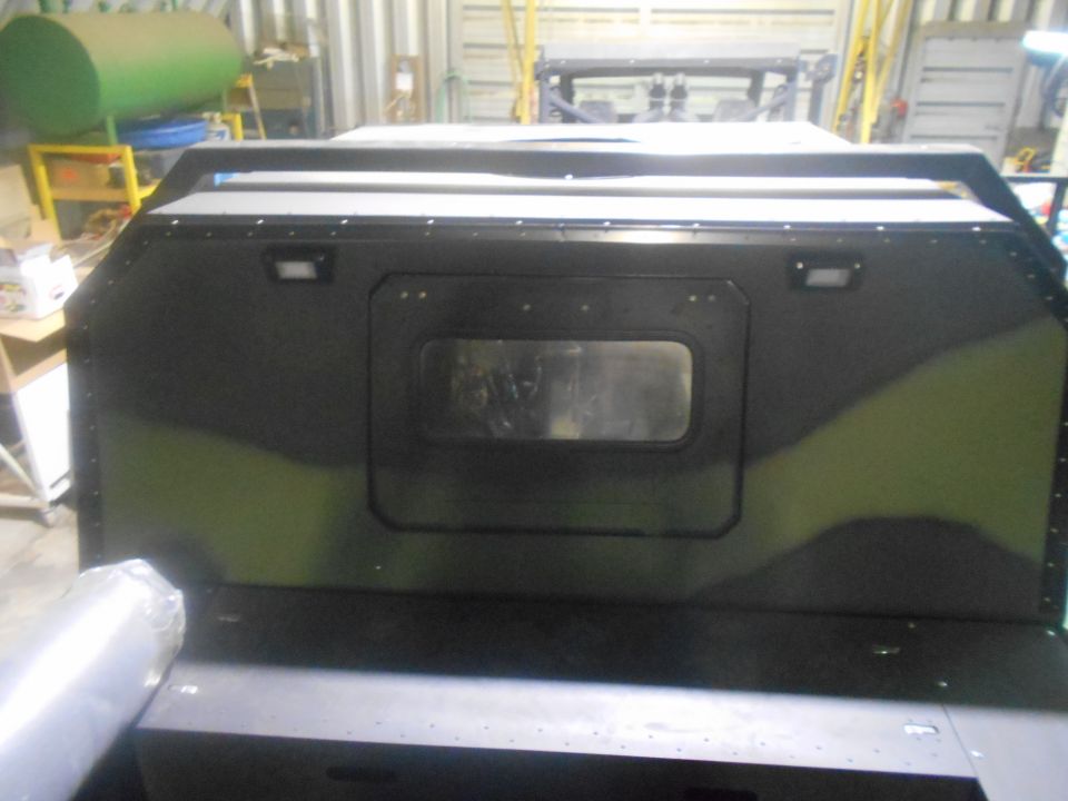 Rear view of a custom vehicle with camouflage paint and a central window.