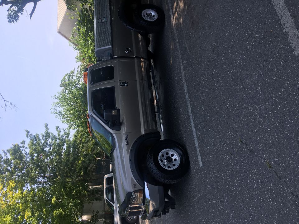 Tan Ford F-250 pickup truck with utility bed, parked on asphalt.