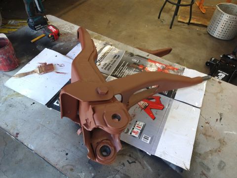 1996 Ford Bronco - A brown painted suspension component, possibly a control arm, sits on top of a box for a 6-ton jack stand. A paintbrush with brown paint is…