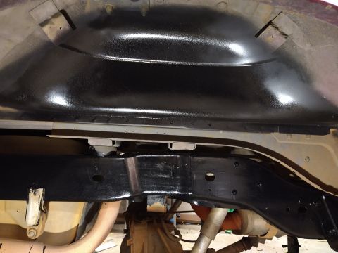 1996 Ford Bronco - The underside of a vehicle's frame and body panels have been coated in a glossy black protective material. Visible are parts of the exhaust…