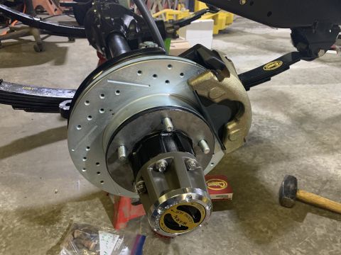 1979 Jeep CJ5 - A close-up view of a newly installed brake rotor, caliper, and Warn locking hub assembly on a vehicle's front axle. The assembly is mounted…