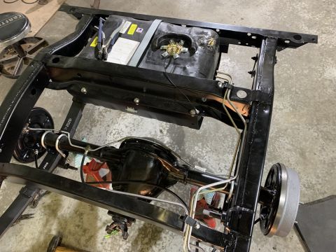 1979 Jeep CJ5 - A black painted Jeep CJ5 frame with a fuel tank and rear axle assembly installed. The rear drum brakes and suspension leaf springs are visi…
