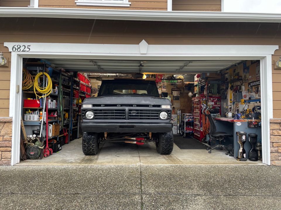 Dark gray lifted Ford pickup truck in an open garage.