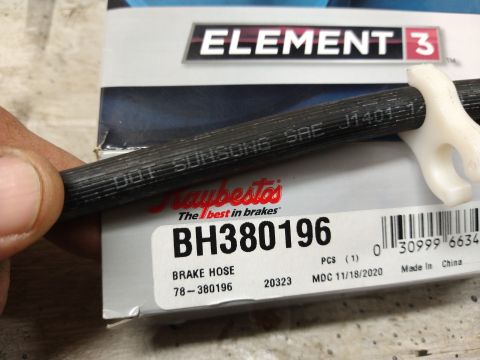 1996 Ford Bronco - A close-up shot of a brake hose with "DOT SUNSONG SAE J1401-1/4" printed on it, resting on packaging for Element 3 brake parts. The packagi…