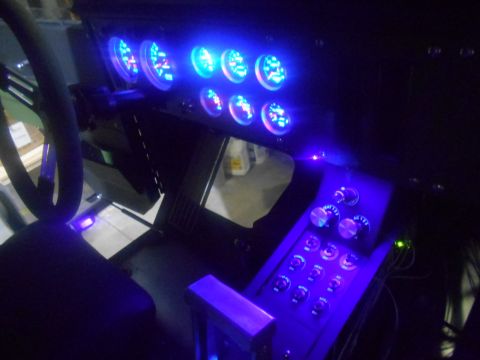 1992 Ford Bronco - The interior of a custom vehicle features a dashboard with multiple blue-lit gauges and a console with several switches and knobs, all illu…
