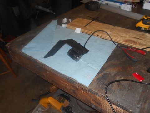 1992 Ford Bronco - A black metal bracket with a small cylindrical component is placed on a blue paper towel on a wooden workbench. Tools and wires are scatter…
