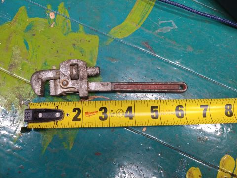 1996 Ford Bronco - A close-up view shows a pipe wrench and a yellow measuring tape laid across a teal surface with green and yellow paint splatters.
