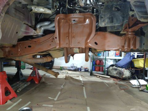 1996 Ford Bronco - The underside of a vehicle, likely a 1996 Ford Bronco, is shown with the frame and suspension components coated in a reddish-brown protecti…