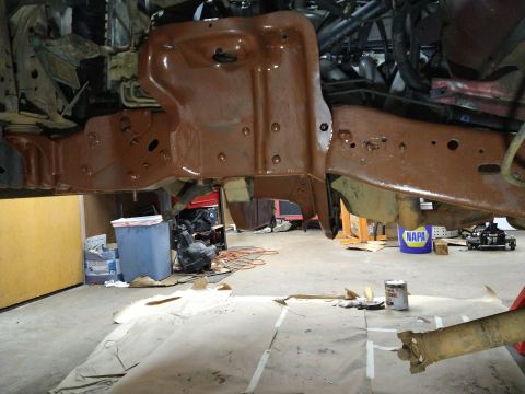 1996 Ford Bronco - The underside of a vehicle, likely a truck or SUV, is shown with the frame and suspension components coated in a reddish-brown protective p…
