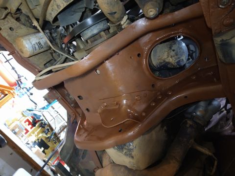 1996 Ford Bronco - A close-up, low-angle view of the underside of a vehicle's frame, which has been painted a glossy brown. Various engine components, hoses,…