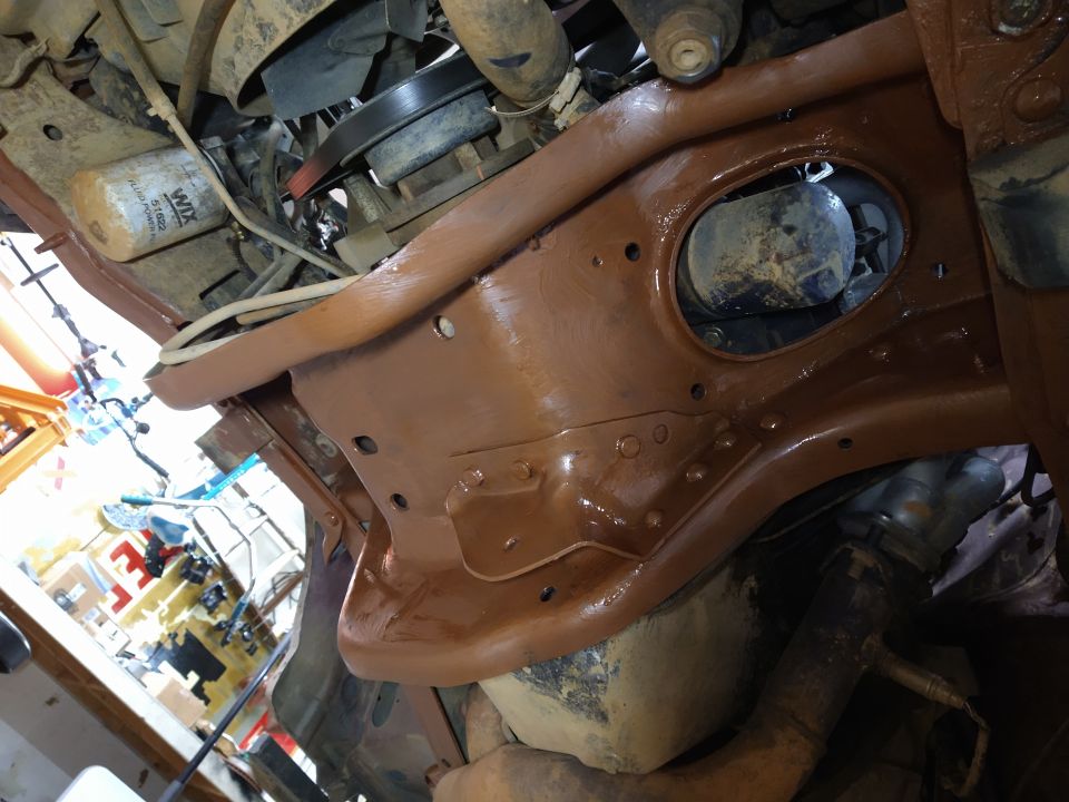Underside of a vehicle frame painted brown, showing engine components and an oil filter.