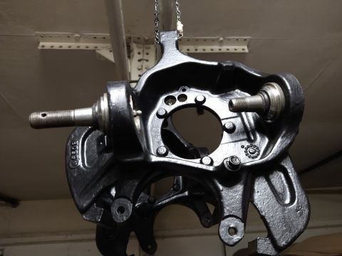 1996 Ford Bronco - A black painted suspension knuckle assembly is hanging from chains. The assembly features threaded studs and various mounting points.