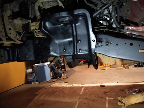 1996 Ford Bronco - The underside of a vehicle, likely a truck or SUV, shows newly painted black frame components and suspension parts. Various hoses and wirin…