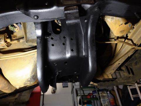 1996 Ford Bronco - The underside of a vehicle shows a freshly painted black metal component, likely a skid plate or frame reinforcement, bolted into place. Va…