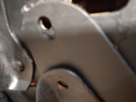 1996 Ford Bronco - Close-up view of two metal brackets with circular holes, likely part of a vehicle's suspension or frame.