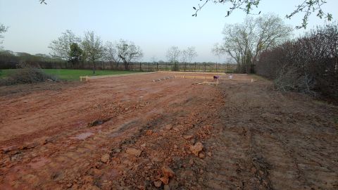 1995 Ford Bronco - A construction site is shown with a wooden foundation frame laid out on the dirt ground, with trees and a fence in the background.