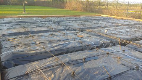 1995 Ford Bronco - Reinforcement grid for a concrete slab, covered with plastic sheeting.