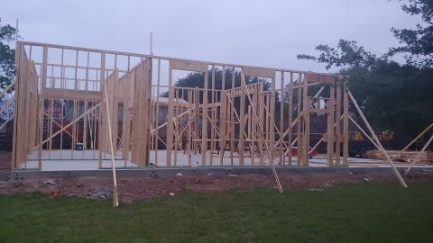 1995 Ford Bronco - The skeletal structure of a building is shown during its construction phase, with wooden beams forming the walls and roof outline.