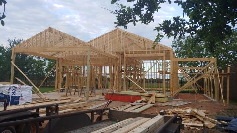 1995 Ford Bronco - House framing in progress, showing the roof and wall structure with construction materials on site.