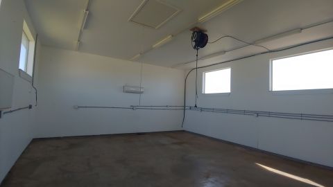 1995 Ford Bronco - This is an empty garage space with lighting, windows, and an air hose reel mounted on the ceiling.