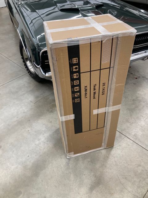1967 Ford Mustang - A cardboard box sits in front of the fender of a dark green 1967 Ford Mustang.