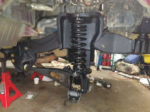 1996 Ford Bronco - Close-up of the front suspension system, showing a newly installed coil spring and control arm during a regear and lift process.