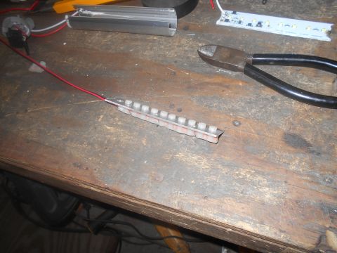 1992 Ford Bronco - A close-up view of a workbench with various electronic components and tools, including LED strips, wires, a switch, and wire cutters.