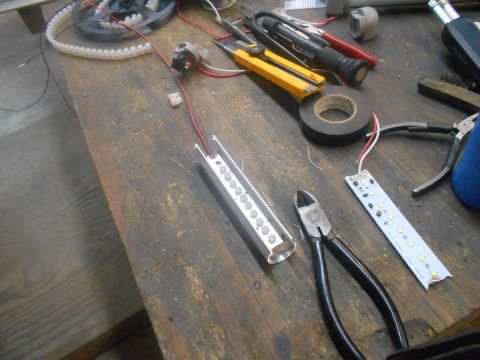 1992 Ford Bronco - A workbench with various electronic components and tools, including LED strips, wire, electrical tape, and wire cutters.