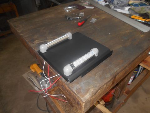 1992 Ford Bronco - A black rectangular housing with two LED light bars and wiring is placed on a wooden workbench. Tools and other items are scattered on the…