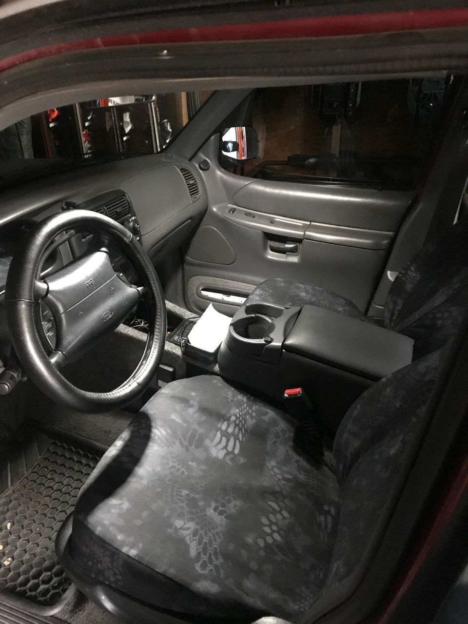 Interior of a Ford Explorer with camouflage seat covers, black steering wheel, and gray dashboard.