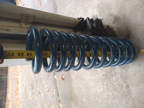 1996 Ford Bronco - A blue coil spring is shown with a yellow measuring tape indicating a length between 17 and 21 inches. The spring is positioned horizontall…